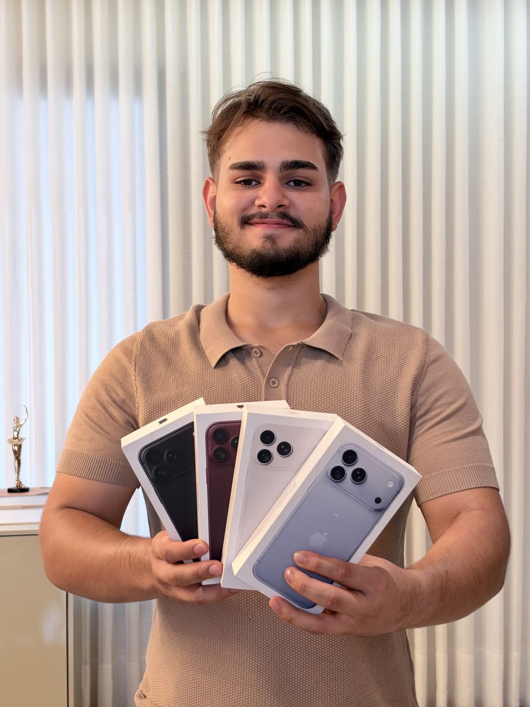 Integrante da equipe Lumari segurando quatro iPhones lacrados em suas caixas